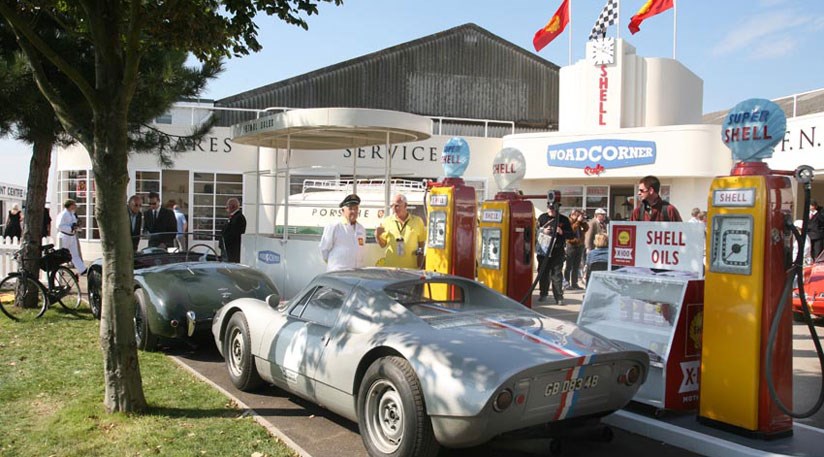 A Porsche 904 pulls up to the pumps in front of the Woad Corner garage display